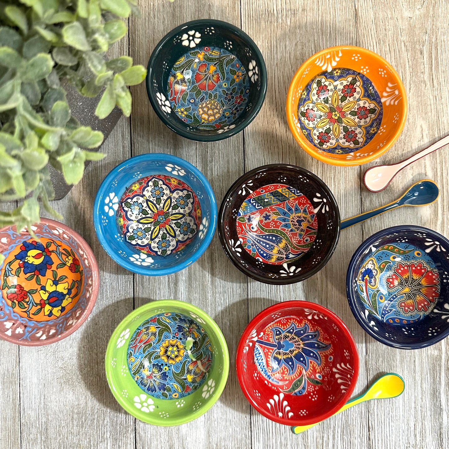 Colorful ceramic bowls with floral patterns on a wooden surface.