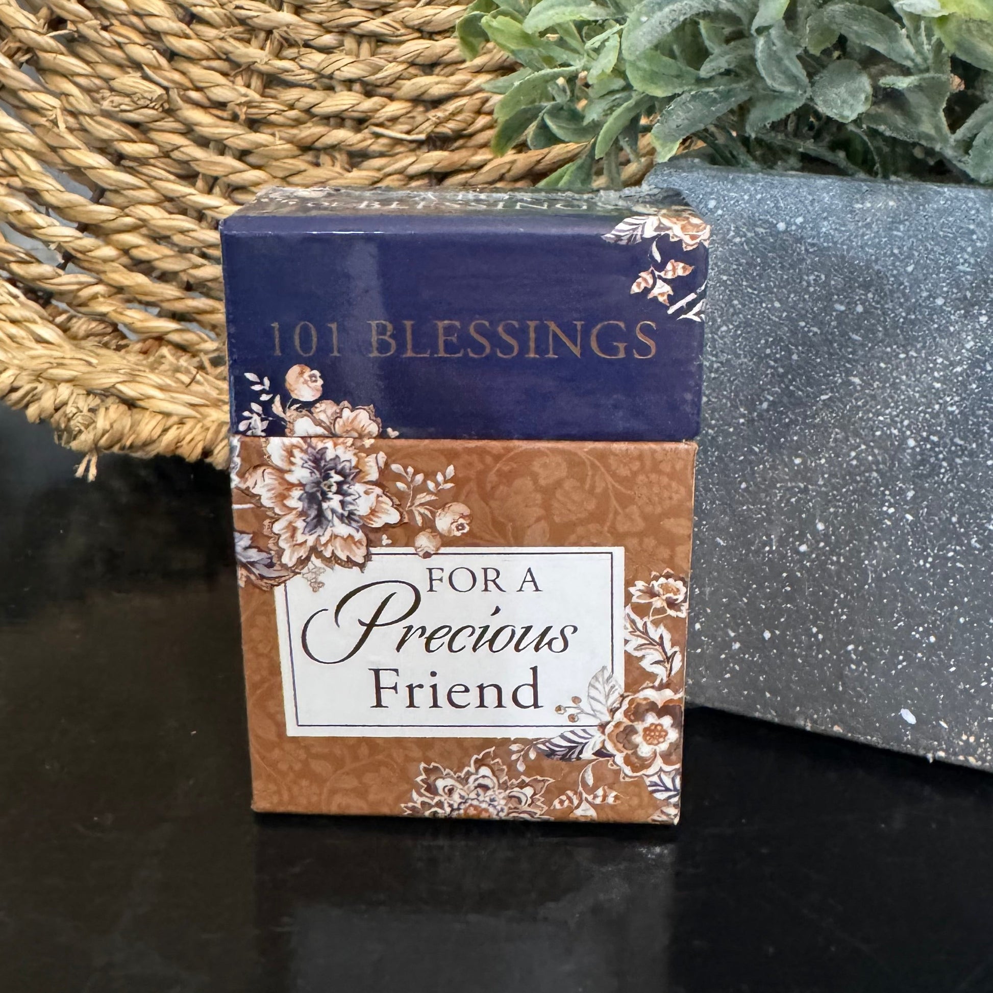 Box of '101 Blessings For a Precious Friend' cards with decorative design on a dark surface.