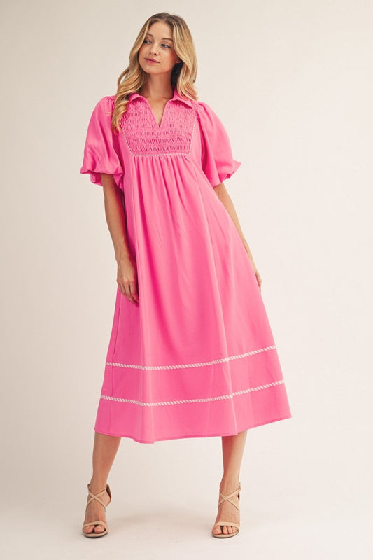 Woman wearing a pink dress with white trim on a beige background