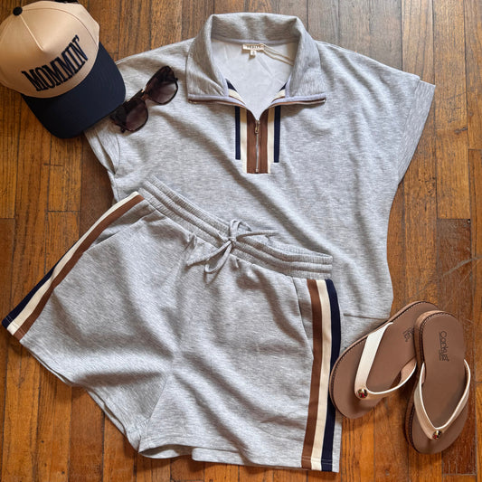 Gray outfit with shorts, tank top, and accessories on a wooden floor