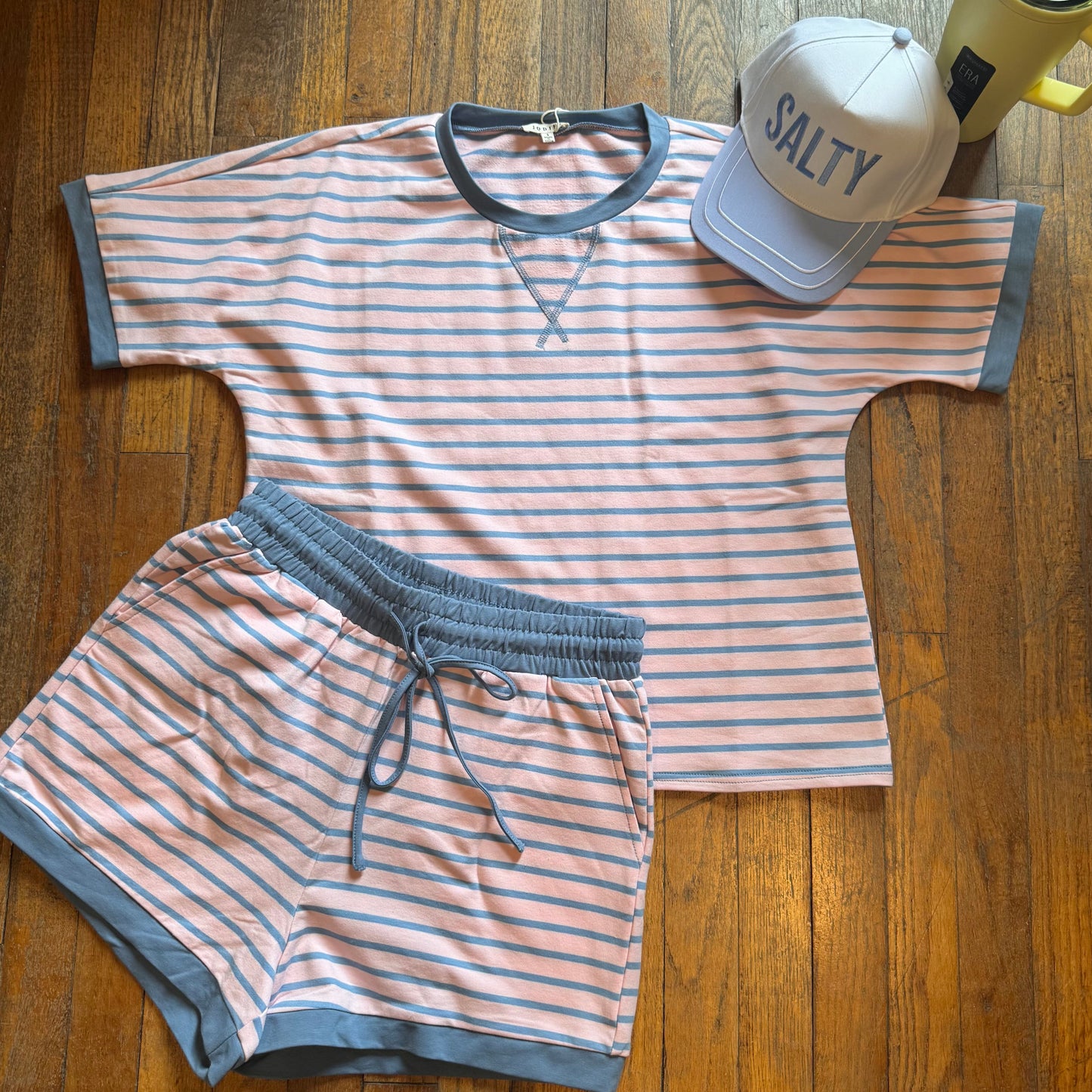 Striped t-shirt and shorts set with a cap and yellow mug on a wooden surface