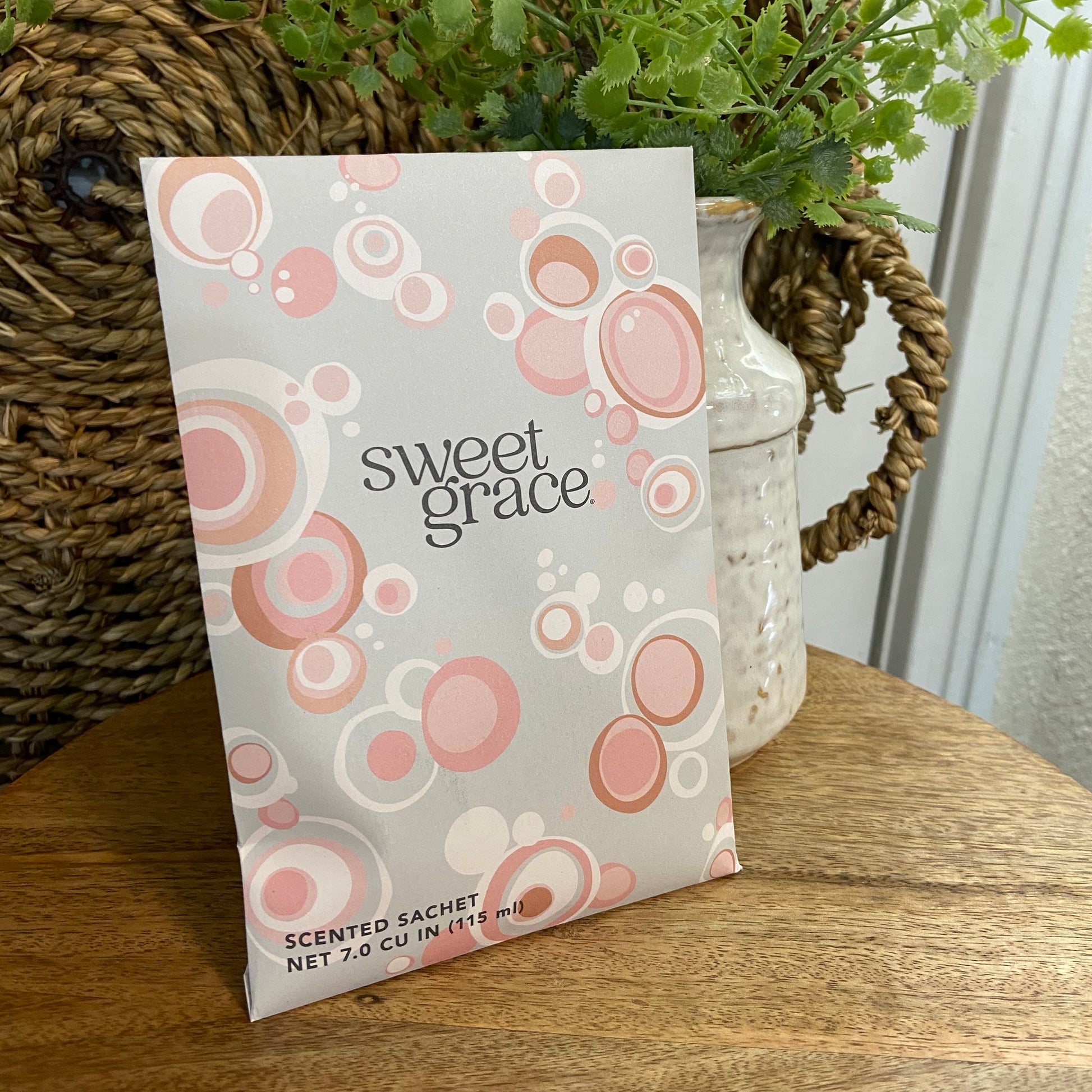 Scented sachet with 'sweet grace' branding on a wooden surface with a plant in the background