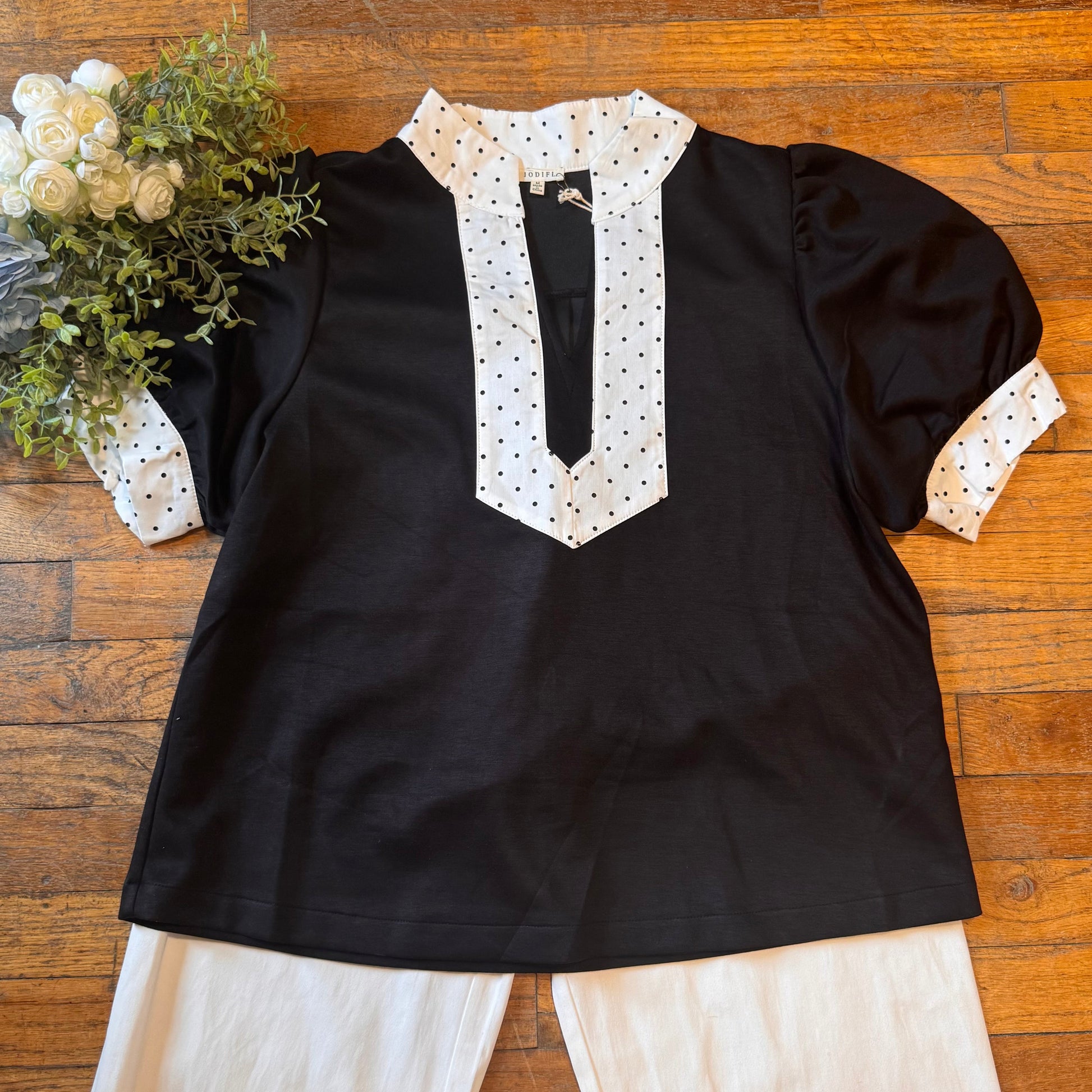 Black top with white polka dot details on a wooden surface