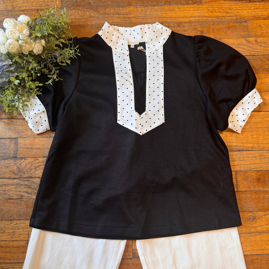 Black top with white polka dot details on a wooden surface