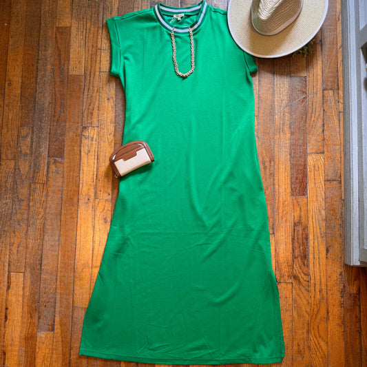 Green garment on a wooden floor with a hat and bag nearby