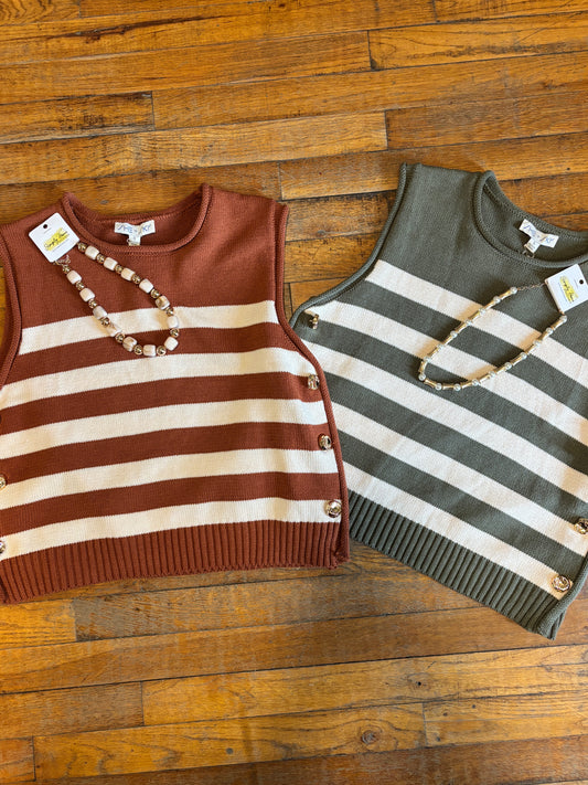 Two sleeveless striped knit vests laid flat on a wooden floor. The vest on the left is rust brown and cream with gold-tone buttons.