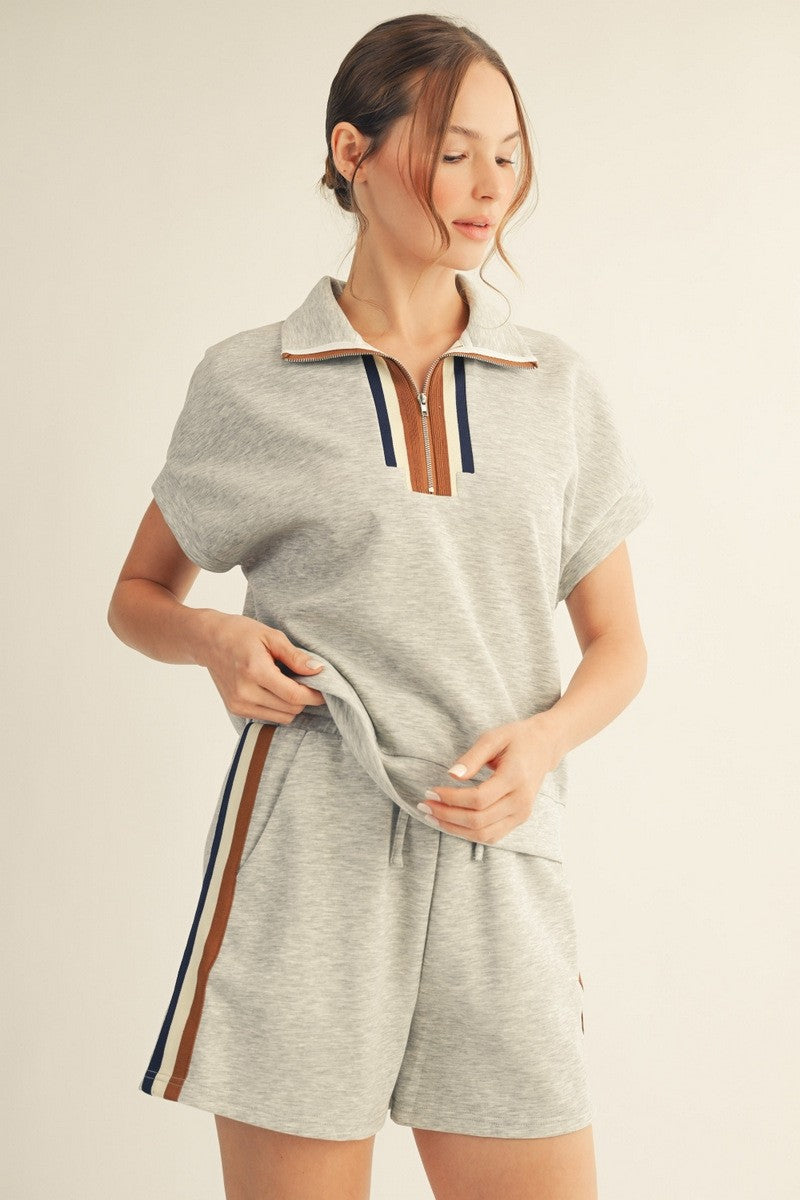 Woman wearing a gray romper with a zipper detail on a beige background